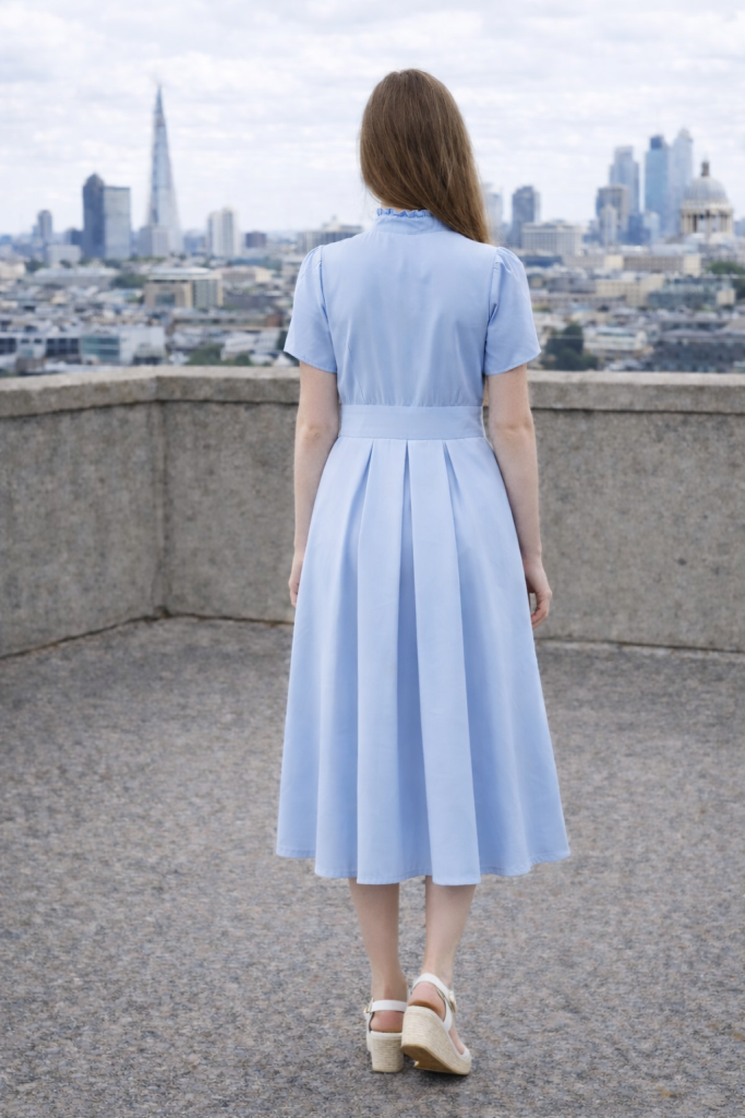 Sky blue midi dress with mother-of-pearl buttons, ruffle front, fitted waist, hidden side-seam pockets, and flowing pleated skirt by BIBI SAKALIEVA